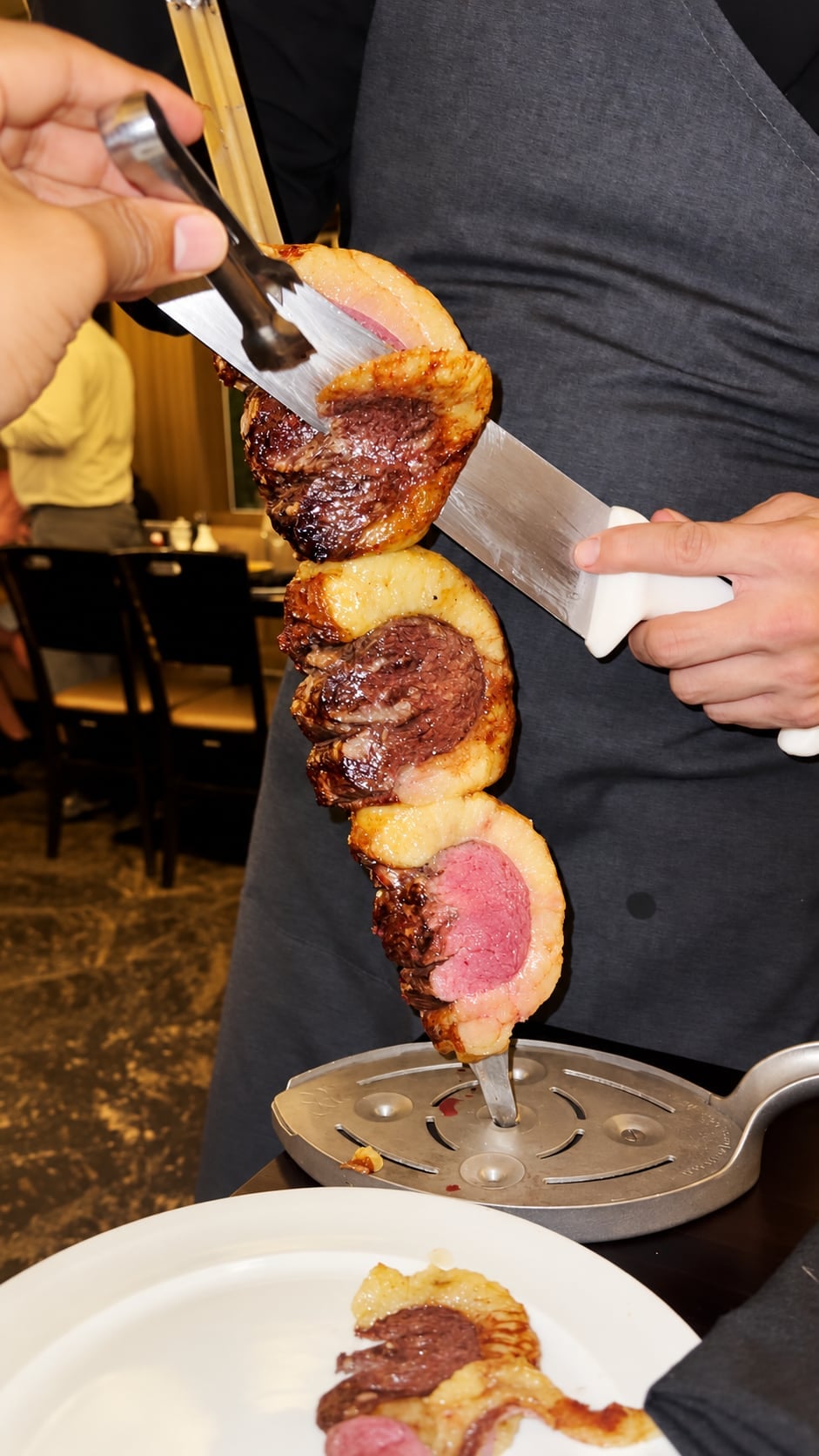 A server carving meat at a restaurant table